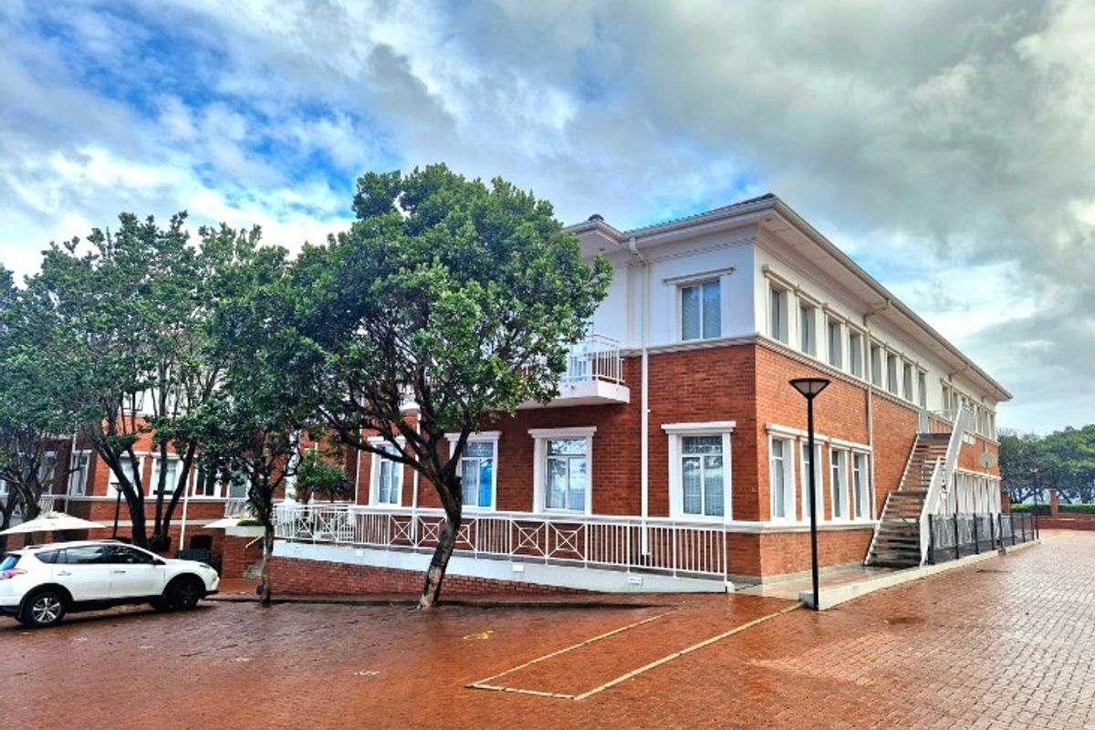 A well-maintained multi-story office building featuring a classic brick facade, external staircase access, and paved exterior grounds.