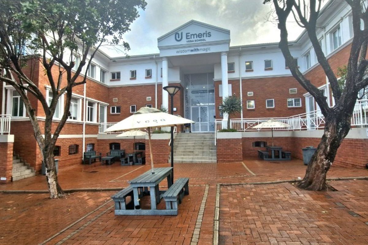 Front exterior view of the office building featuring a brick facade, central entrance with columns, and a paved courtyard area.