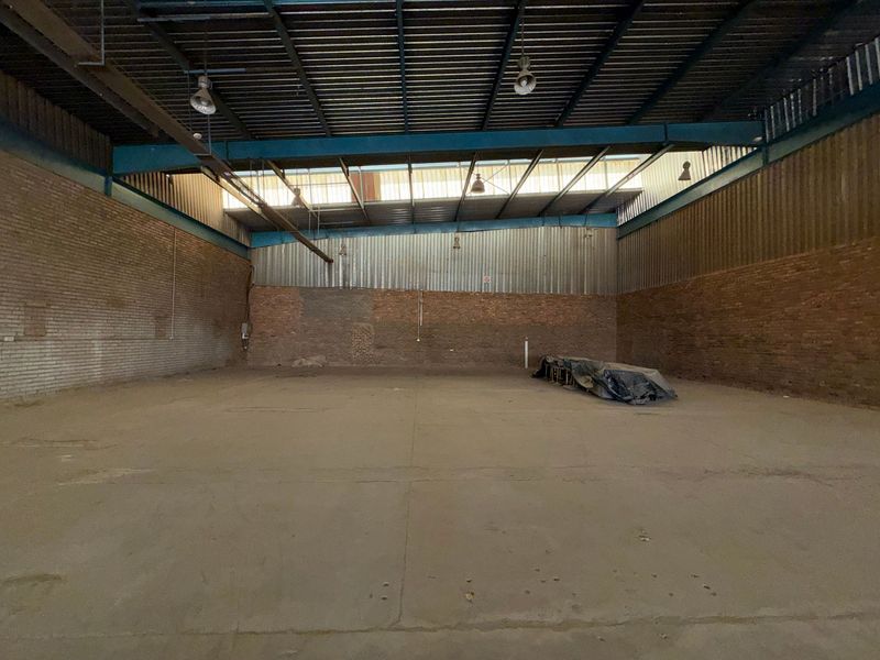 Spacious industrial warehouse unit featuring high ceilings, exposed brick walls, concrete flooring, and ample natural light through clerestory windows.