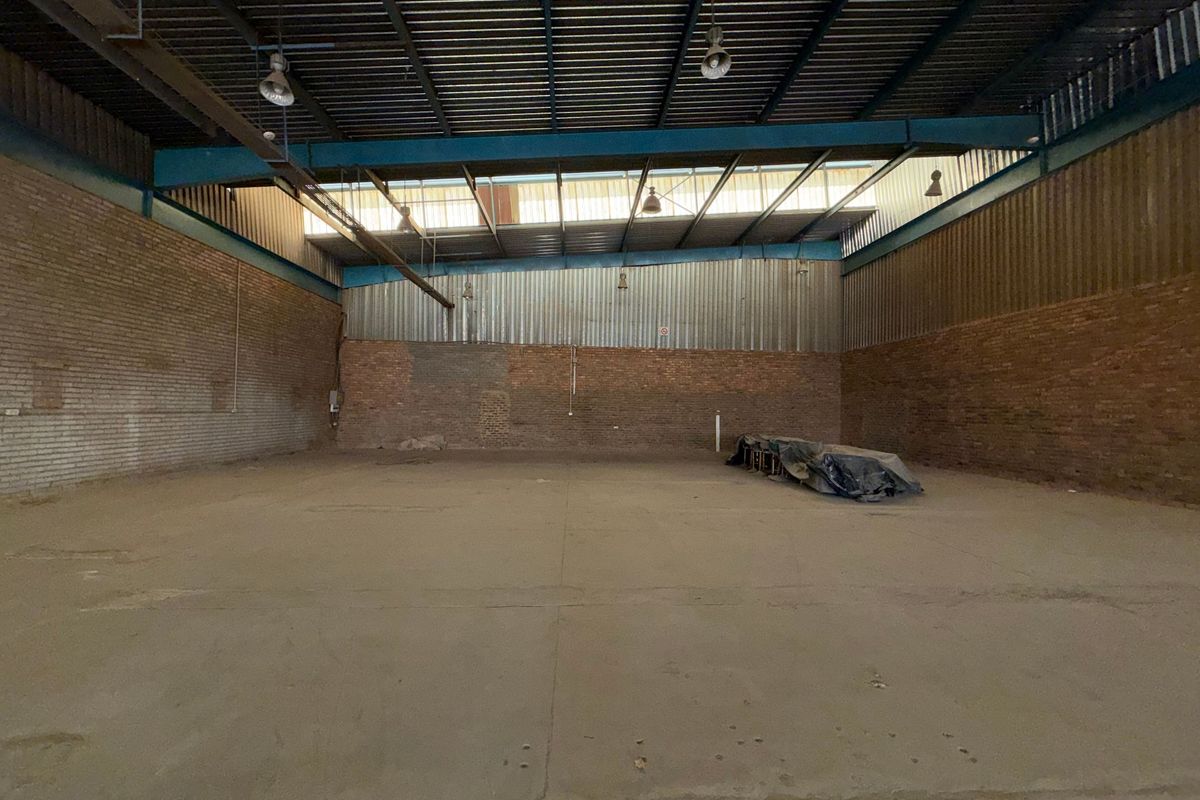 Spacious industrial warehouse unit featuring high ceilings, exposed brick walls, concrete flooring, and ample natural light through clerestory windows.