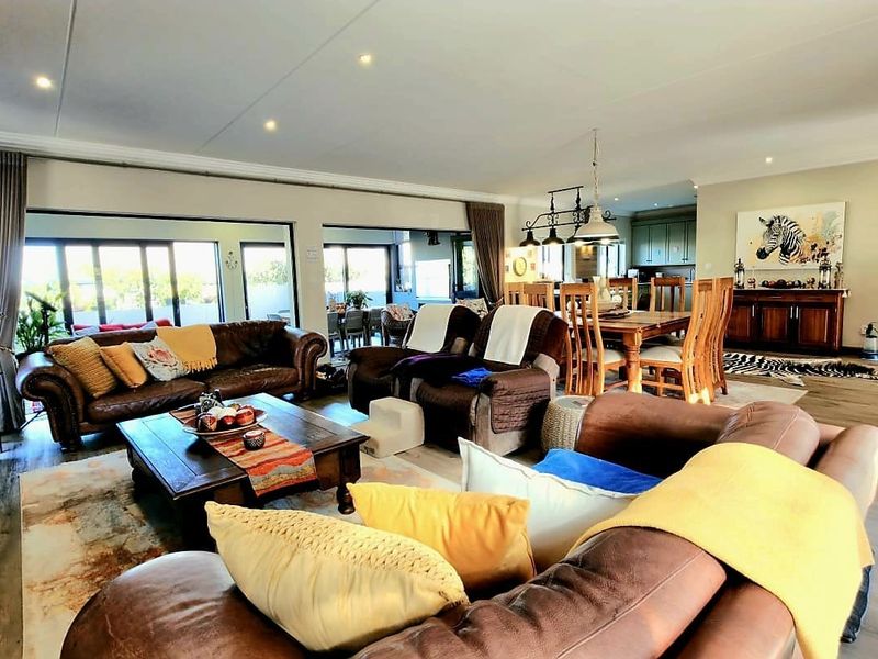 Spacious open-plan living and dining area featuring laminate flooring, recessed lighting, and large sliding glass doors leading to an outdoor space.