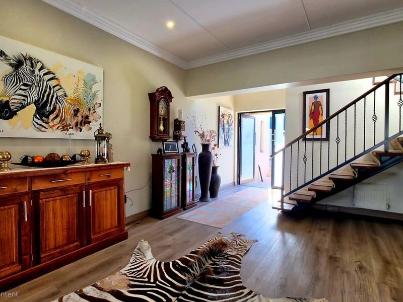 Welcoming entrance hall featuring a modern staircase with wrought iron balustrade, crown molding, and durable laminate flooring.