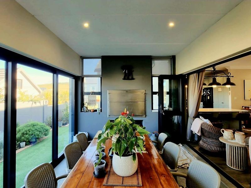 A covered patio area featuring a built-in braai, large sliding glass doors, and recessed lighting, seamlessly connecting to the indoor living space.