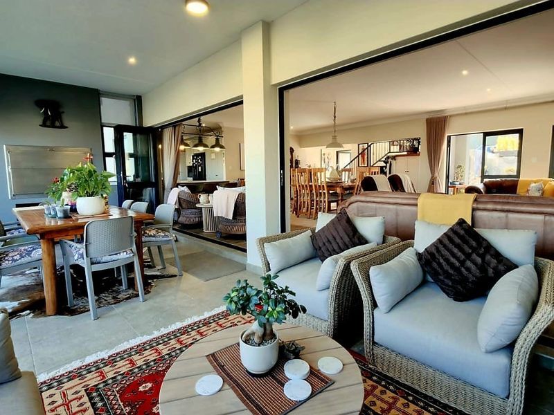 Spacious covered patio featuring a built-in braai, recessed lighting, and large sliding doors that provide seamless flow into the open-plan living and dining area.