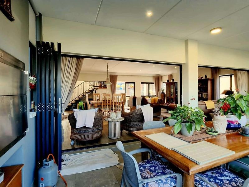 Covered patio area featuring a built-in braai and large stacking doors that provide seamless flow into the open-plan living and dining space.