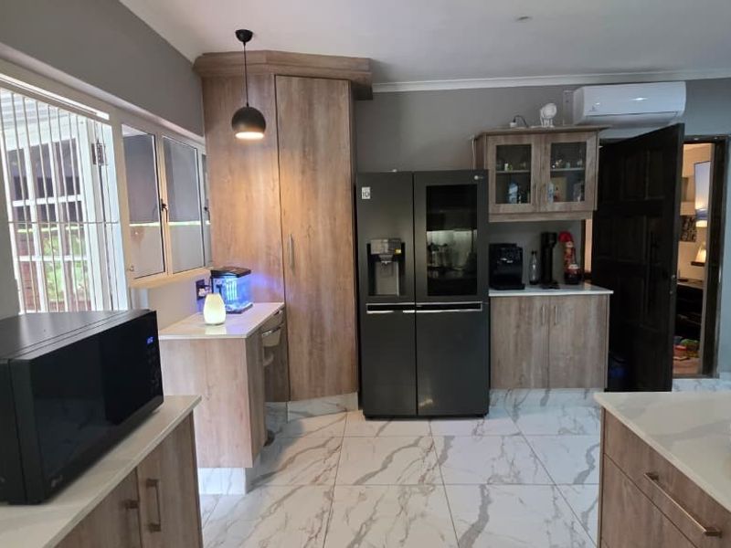 Modern kitchen featuring wood-finish cabinetry, stone countertops, marble-look floor tiles, and an integrated air conditioning unit.