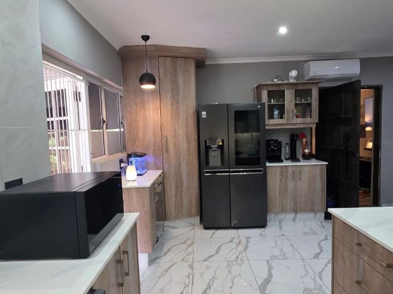 Modern kitchen featuring wood-finish cabinetry, stone countertops, marble-look floor tiles, and integrated lighting, offering a clean and contemporary aesthetic.