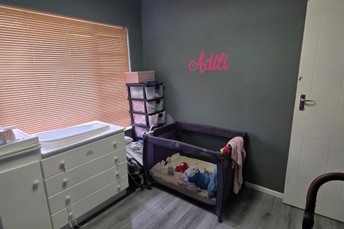 A bedroom featuring grey walls, laminate flooring, and venetian blinds, providing a functional space with neutral base finishes.