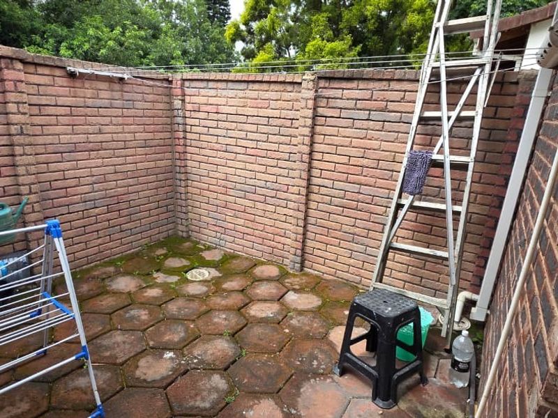A small, enclosed rear courtyard area featuring brick boundary walls and paved flooring, suitable for a private utility or garden space.