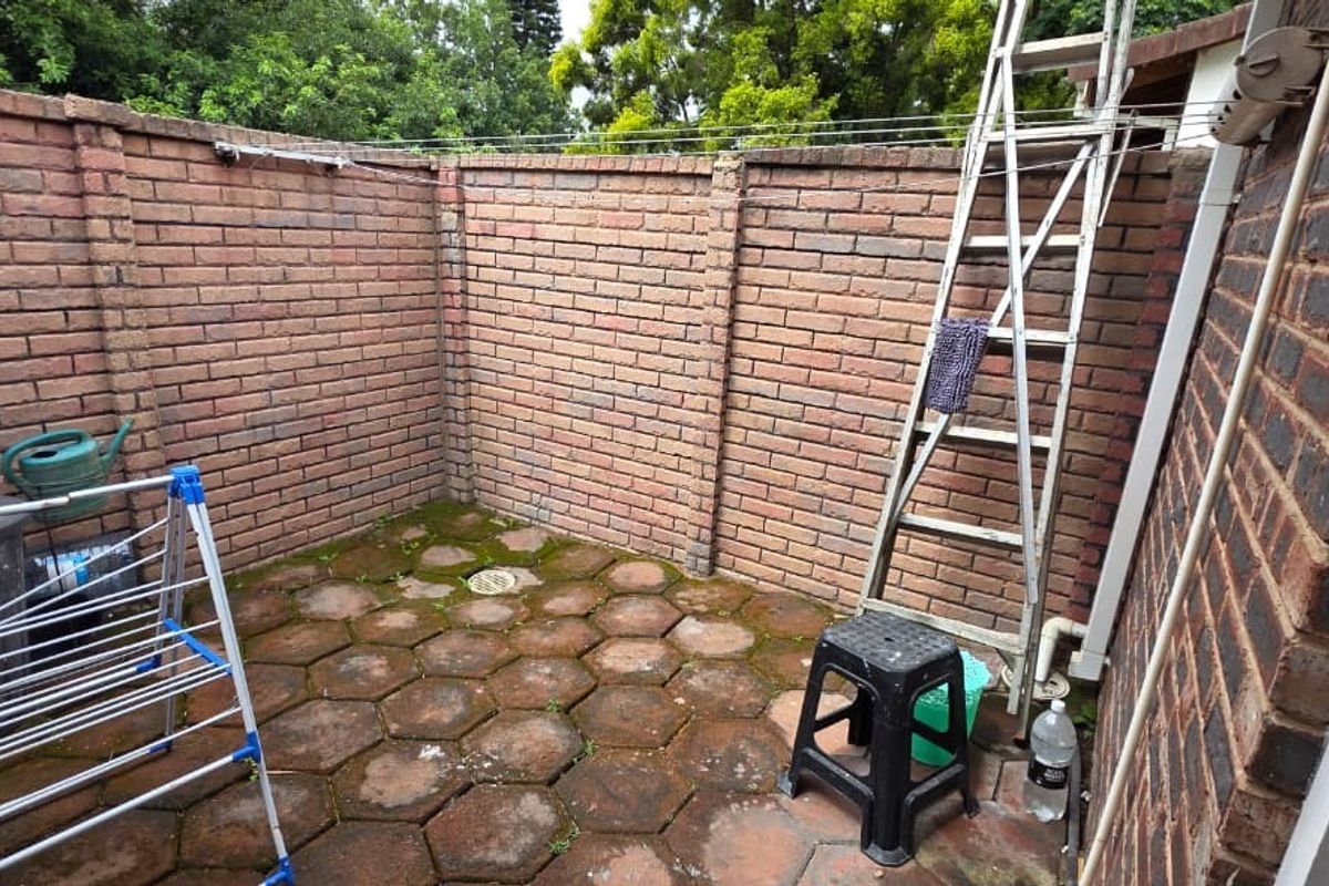 A small, enclosed rear courtyard area featuring brick boundary walls and paved flooring, suitable for a private utility or garden space.