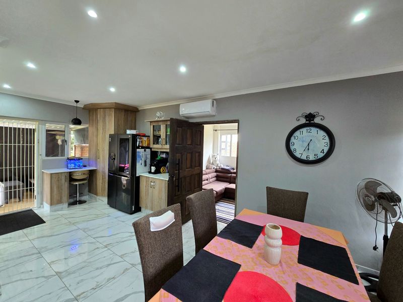 Open-plan living and dining area featuring modern tiled flooring, recessed lighting, and a split-system air conditioner, providing a functional and connected living space.