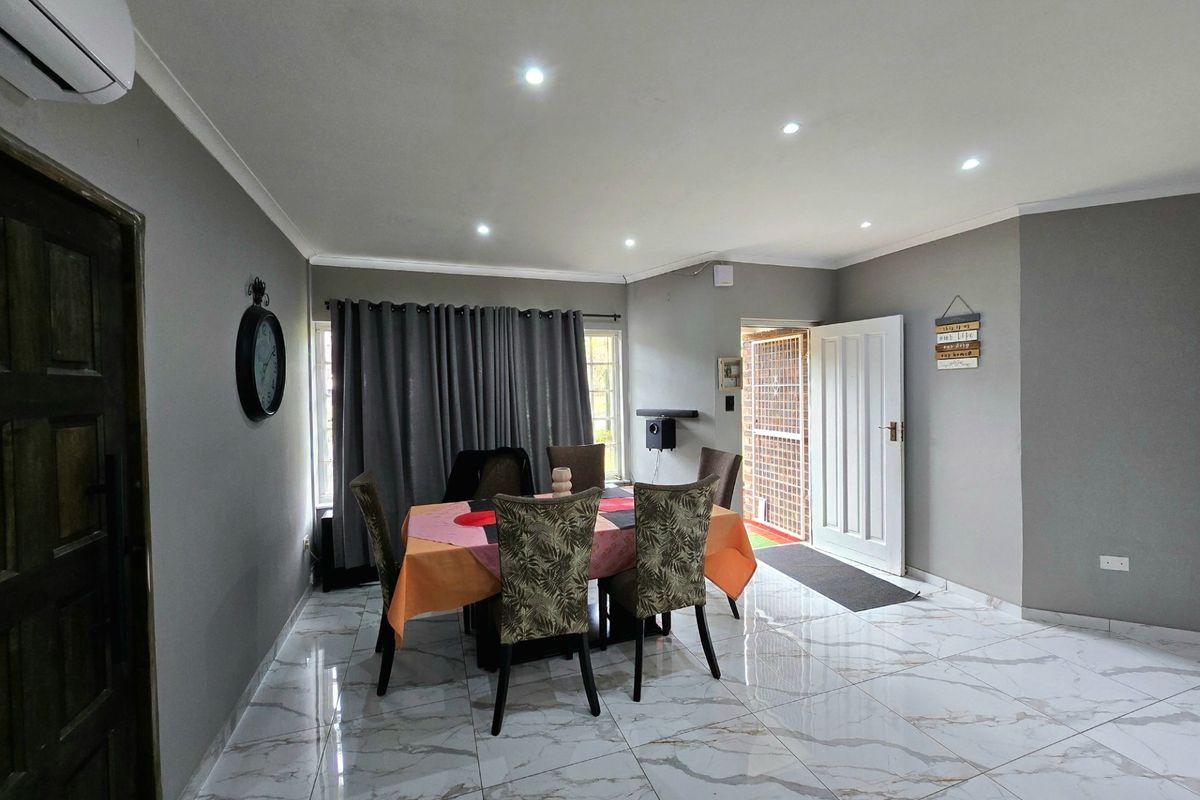 Open-plan living and dining area featuring polished marble-look floor tiles, recessed downlighting, and a wall-mounted air conditioning unit.