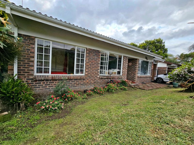 Front exterior view of a face brick townhouse featuring grid-pattern windows, a paved entrance path, and a front garden area.