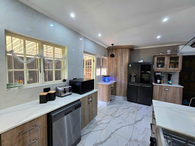 Modern kitchen featuring wood-grain cabinetry, stone countertops, marble-look floor tiles, and integrated appliances, offering a clean and contemporary aesthetic.