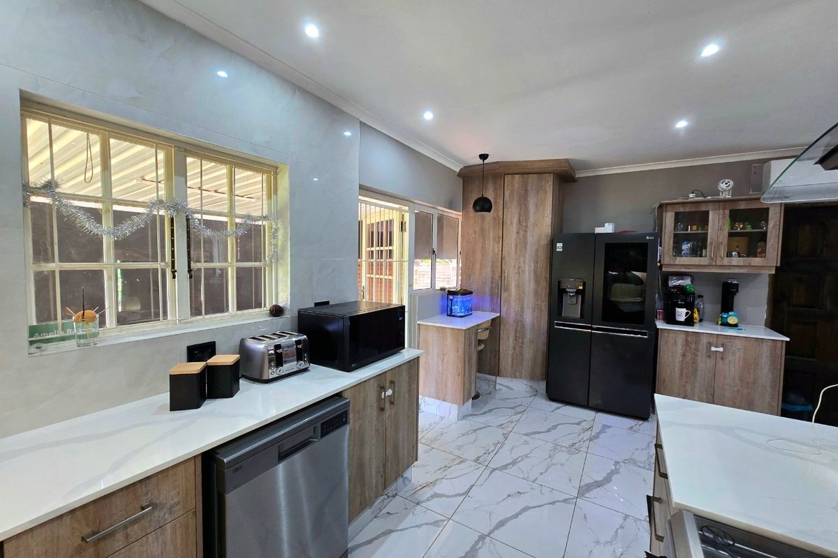 Modern kitchen featuring wood-grain cabinetry, stone countertops, marble-look floor tiles, and integrated appliances, offering a clean and contemporary aesthetic.