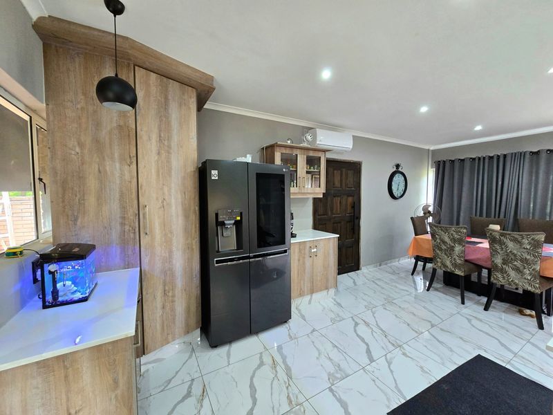 Open-plan living and dining area featuring modern marble-look floor tiles, recessed lighting, and built-in cabinetry with a neutral color palette.