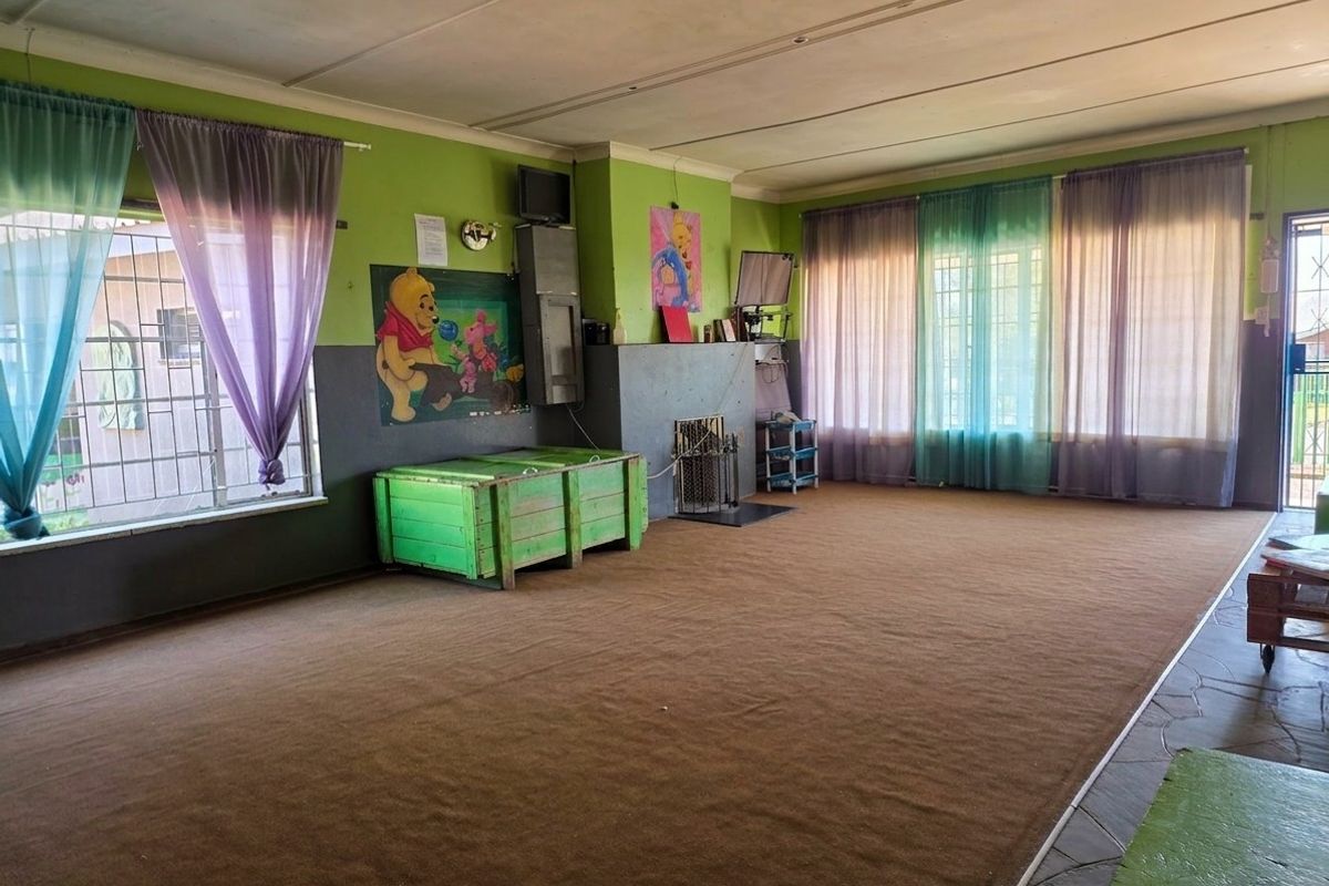 Spacious living room featuring a fireplace, security bars on windows, and carpeted flooring, offering a blank canvas for renovation and modernization.