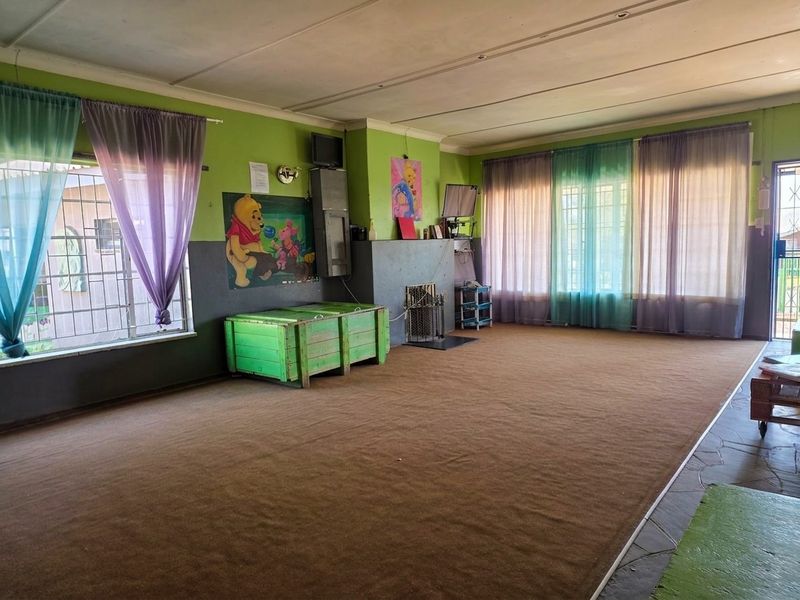 Spacious living room featuring a fireplace, security bars on windows, and carpeted flooring, offering a blank canvas for renovation and modernization.