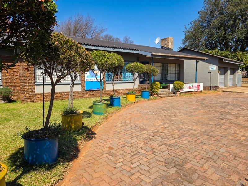 Front exterior view of the property featuring a brick driveway, stone chimney, and security bars on the windows.