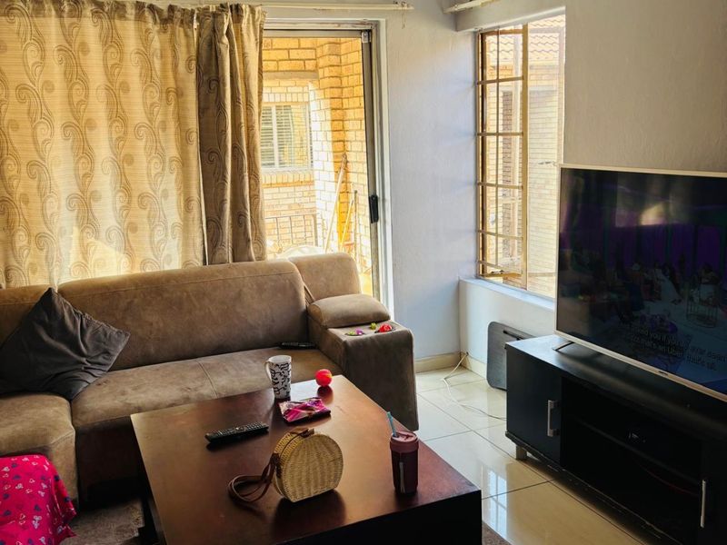 A living room featuring tiled flooring, a sliding glass door leading to an outdoor area, and a window with security bars.
