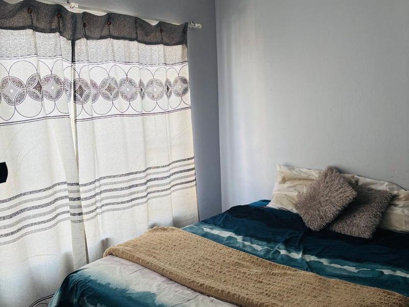 A bedroom featuring neutral wall paint and a window fitted with a curtain rod.