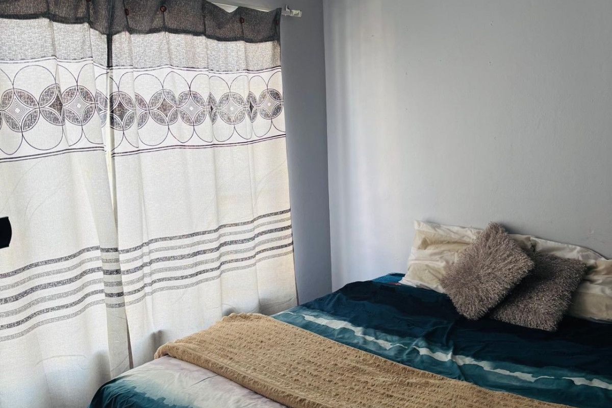 A bedroom featuring neutral wall paint and a window fitted with a curtain rod.