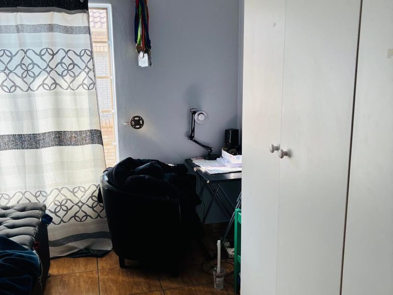 A bedroom featuring tiled flooring and a built-in wardrobe, providing functional storage space within the room.
