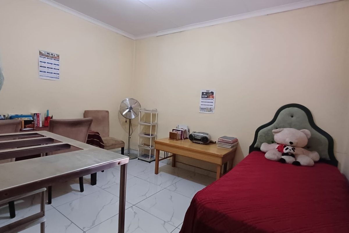 A functional bedroom featuring tiled flooring and window blinds, offering a neutral space ready for personalization.