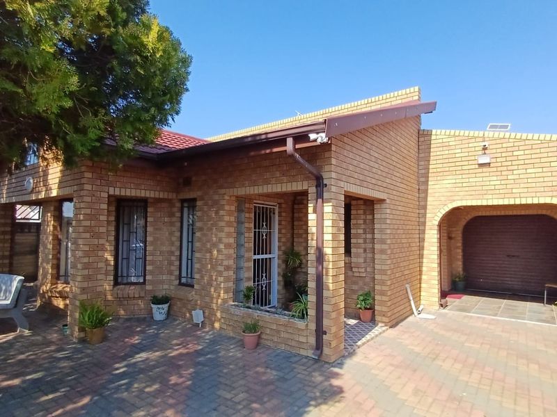 A well-maintained face brick house featuring a paved driveway, integrated garage, and secure entrance with security gate.