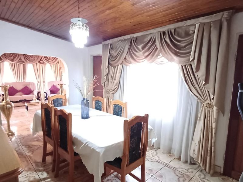 Dining room featuring a timber tongue and groove ceiling, ceramic floor tiles, and an arched opening leading to an adjacent living area.