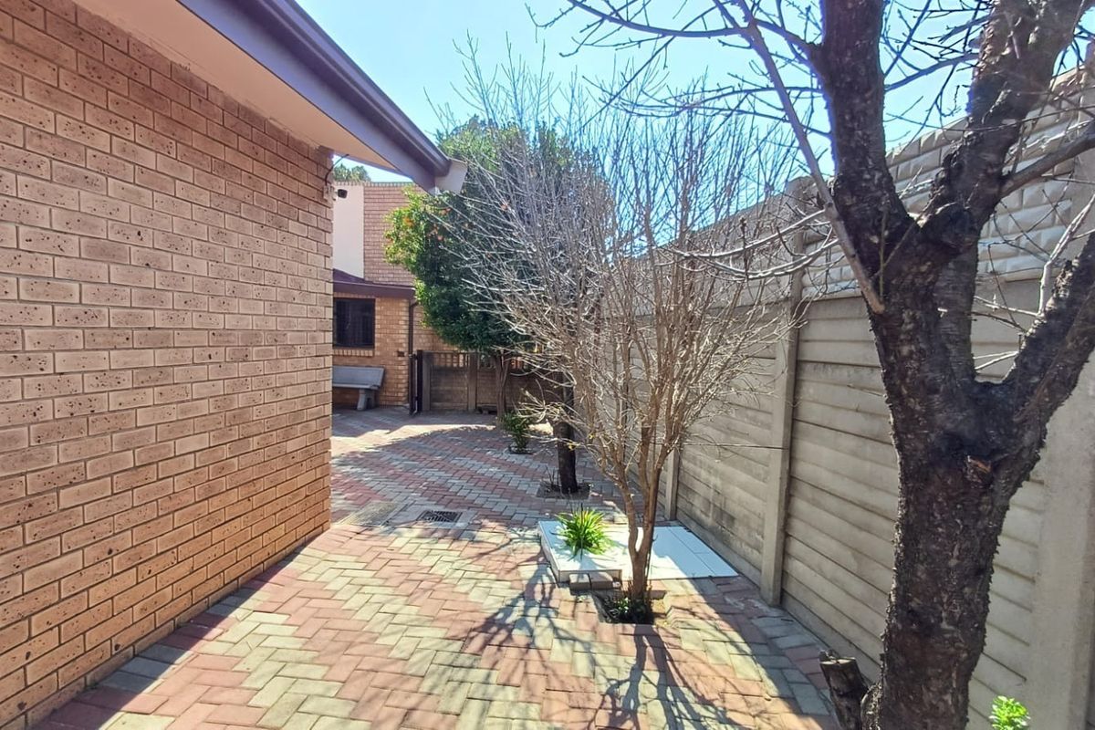 A paved rear courtyard area featuring brick wall construction and perimeter precast concrete fencing.