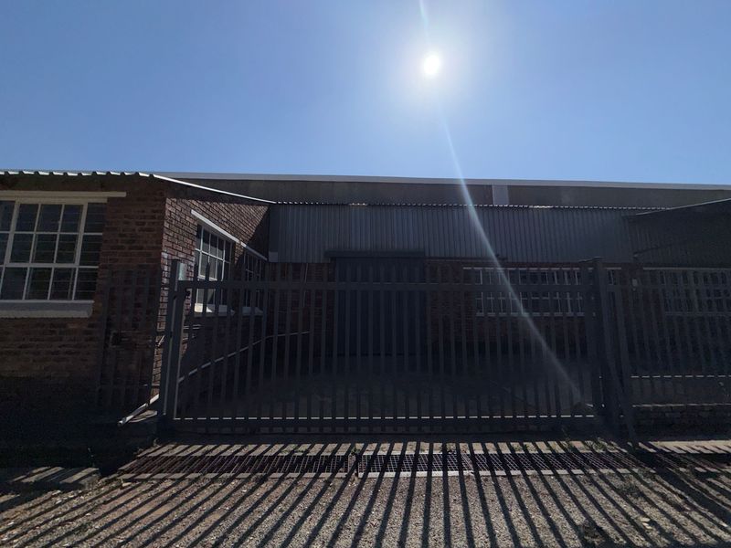 Front exterior view of an industrial property featuring brick masonry, metal cladding, and a secure gated entrance.