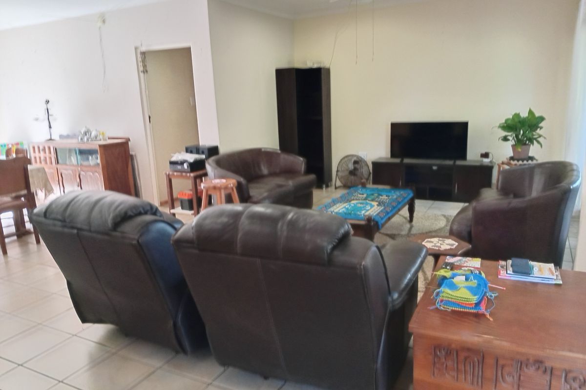 A spacious living room featuring tiled flooring and a ceiling fan, offering a functional layout for comfortable family living.