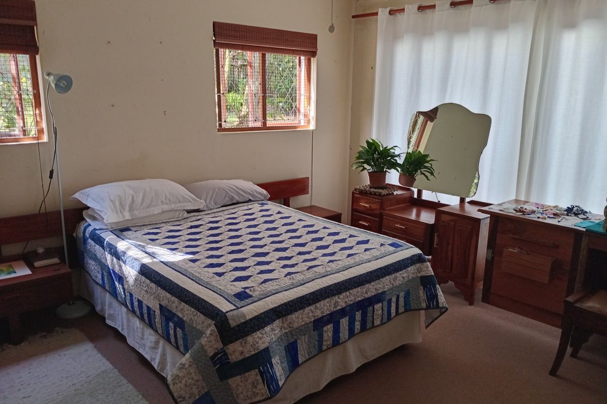 A bedroom featuring carpeted flooring, security bars on the windows, and a built-in headboard, requiring minor wall repairs and cosmetic updates.