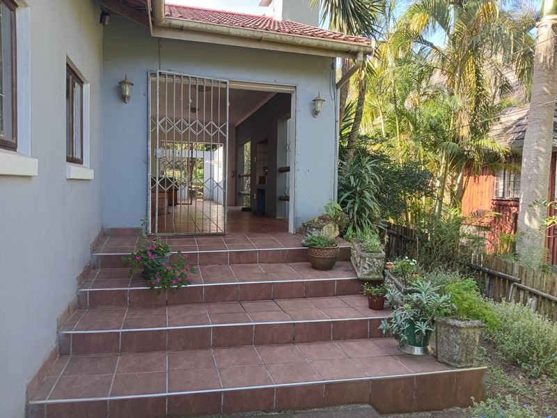 Rear exterior view featuring a tiled patio area with steps leading to an entrance secured by a metal gate.