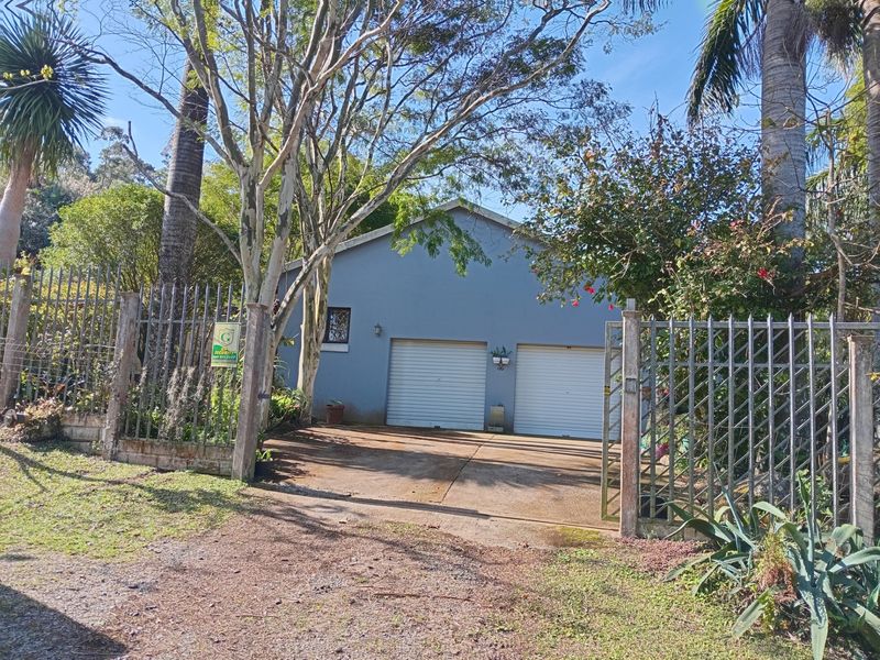 A detached double garage with roll-up doors, accessed via a concrete driveway and secured by metal fencing and a gate.