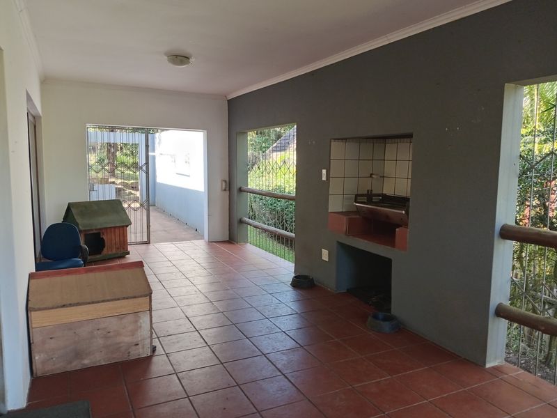 Covered patio area featuring a built-in braai, tiled flooring, and security gates, providing a functional outdoor entertainment space.