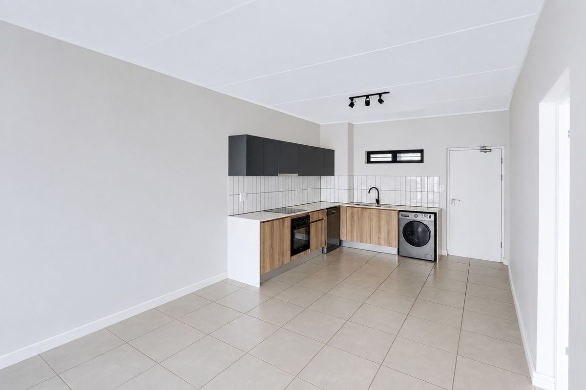 Modern, clean-lined kitchen featuring wood-finish cabinetry, dark overhead cupboards, built-in oven and hob, tiled backsplash, and neutral floor tiles in an open-plan layout.