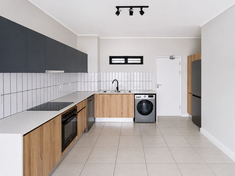 Modern kitchen featuring sleek wood-grain and charcoal cabinetry, white quartz countertops, subway tile backsplash, and integrated appliances in a clean, minimalist layout.