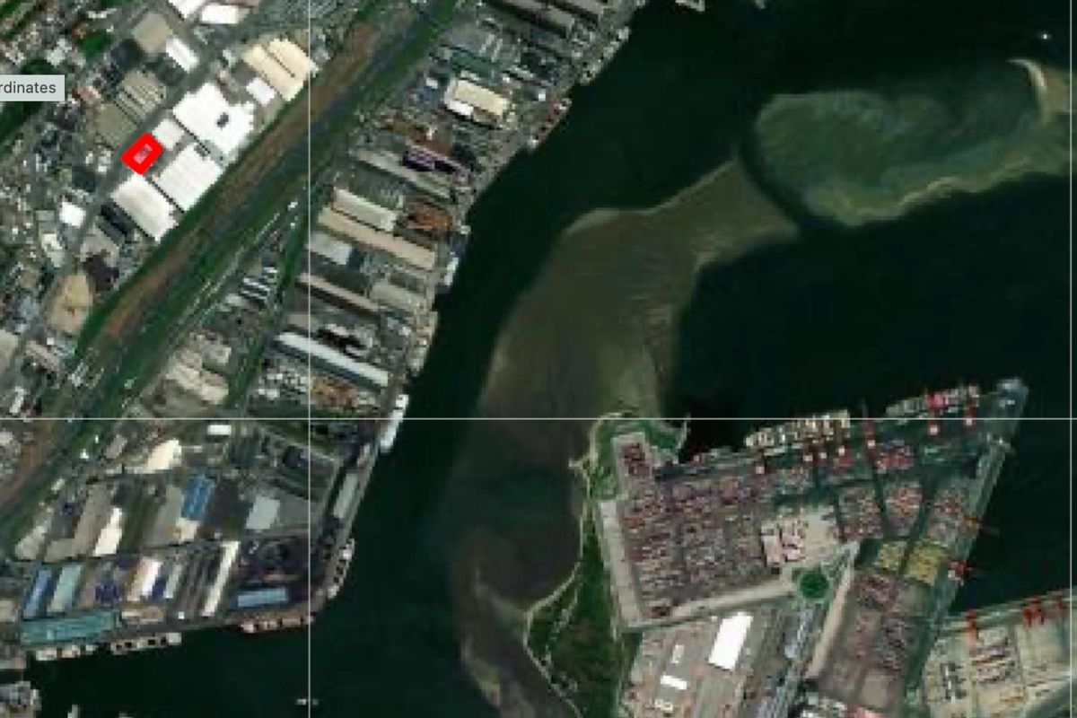 Aerial view of a commercial industrial zone located near a harbour and port facilities.