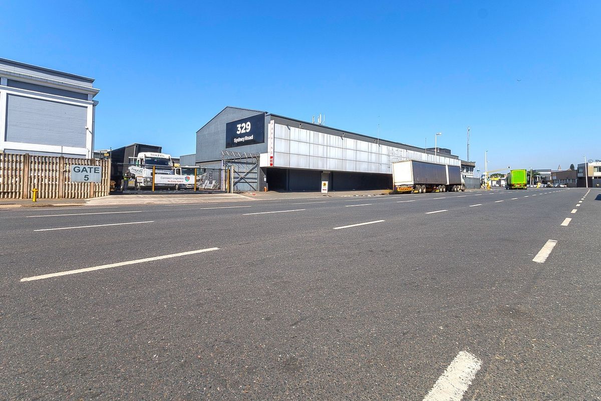 Street view of a commercial industrial property located at 329 Sydney Road, featuring warehouse frontage and secure gated access.