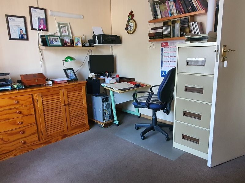 A functional home office space featuring carpeted flooring and built-in shelving, providing a dedicated area for work or study.