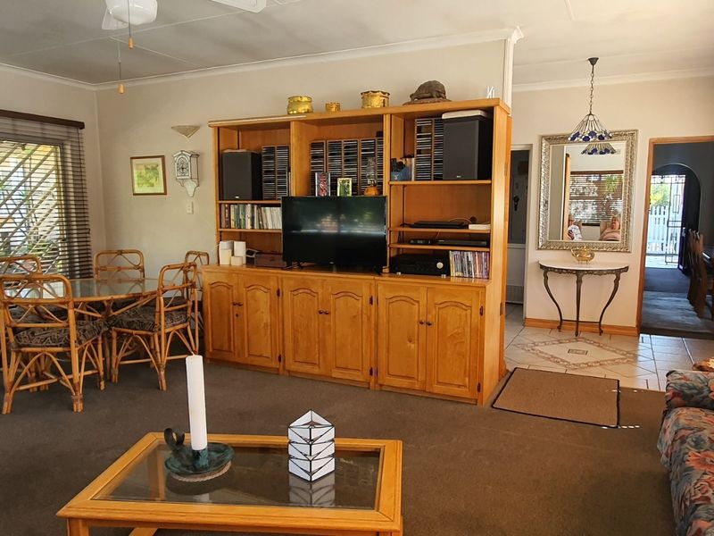 Spacious living area featuring built-in wooden cabinetry, sliding glass doors leading to the patio, and a combination of tiled and carpeted flooring.