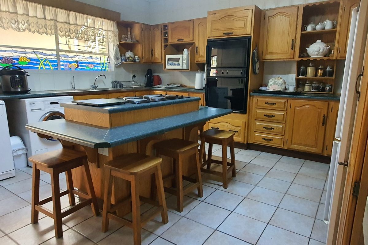 A spacious kitchen featuring extensive wooden cabinetry, a central island with seating, built-in oven, and a decorative stained glass window above the sink area.