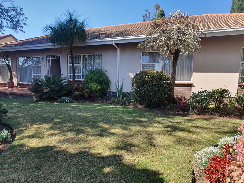 A well-maintained single-story residential home featuring a tiled roof, security bars on windows, and a landscaped front garden.