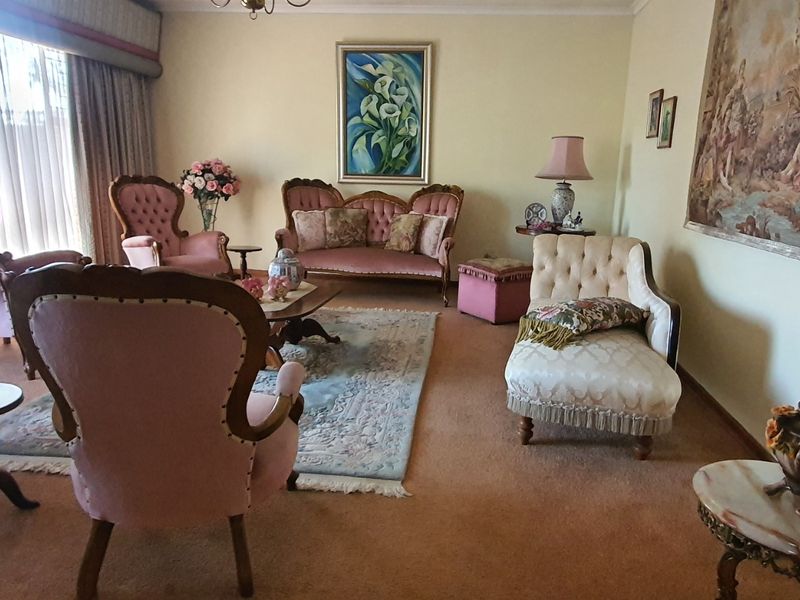 A traditional living room featuring carpeted flooring and large window treatments, offering a spacious area for relaxation.