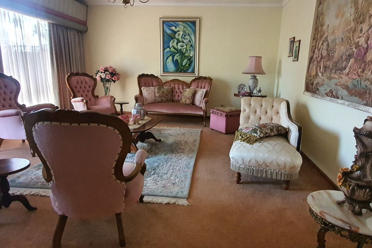 A traditional living room featuring carpeted flooring and large window treatments, offering a spacious area for relaxation.