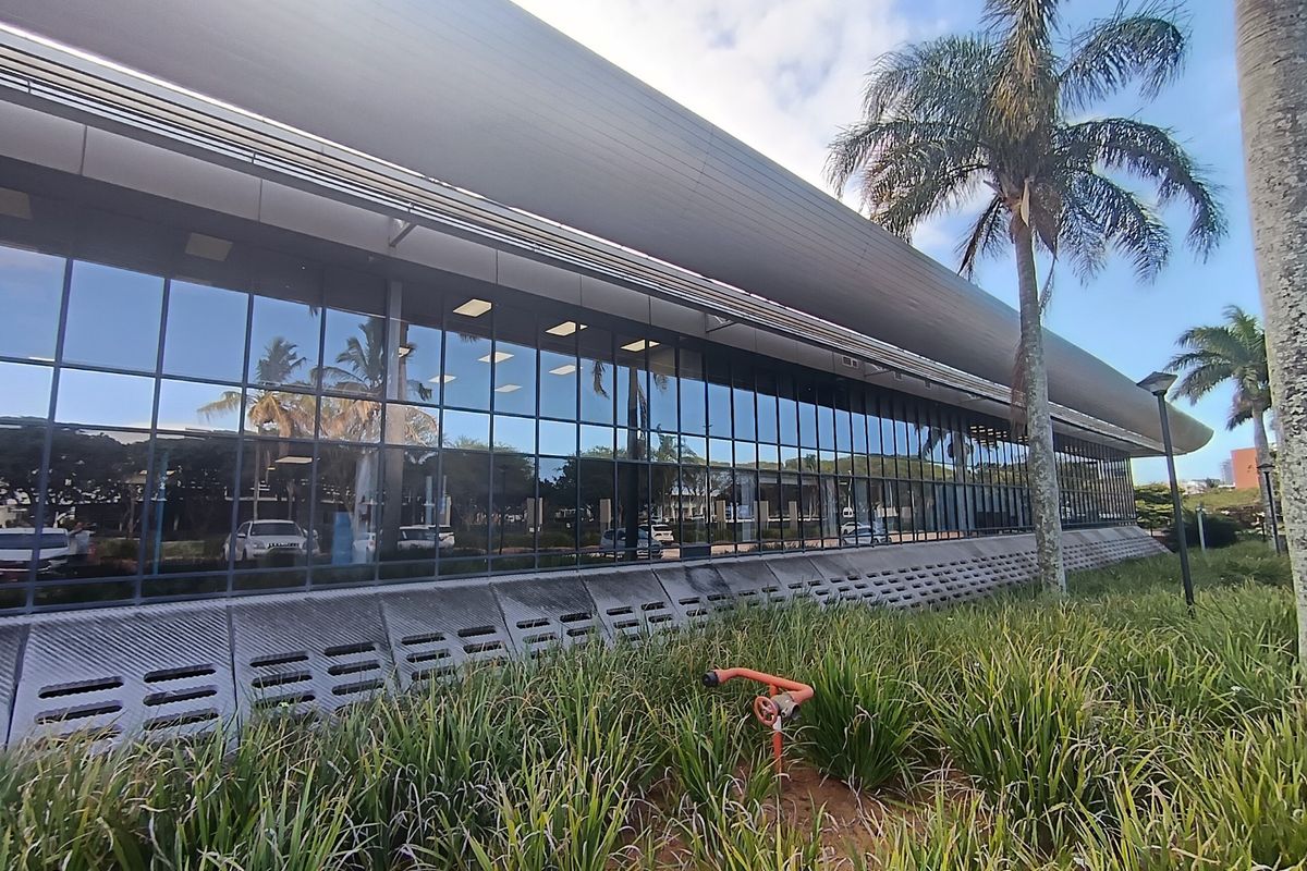 Modern office building exterior featuring extensive glass curtain walling, a distinctive curved roofline, and integrated ventilation base panels.
