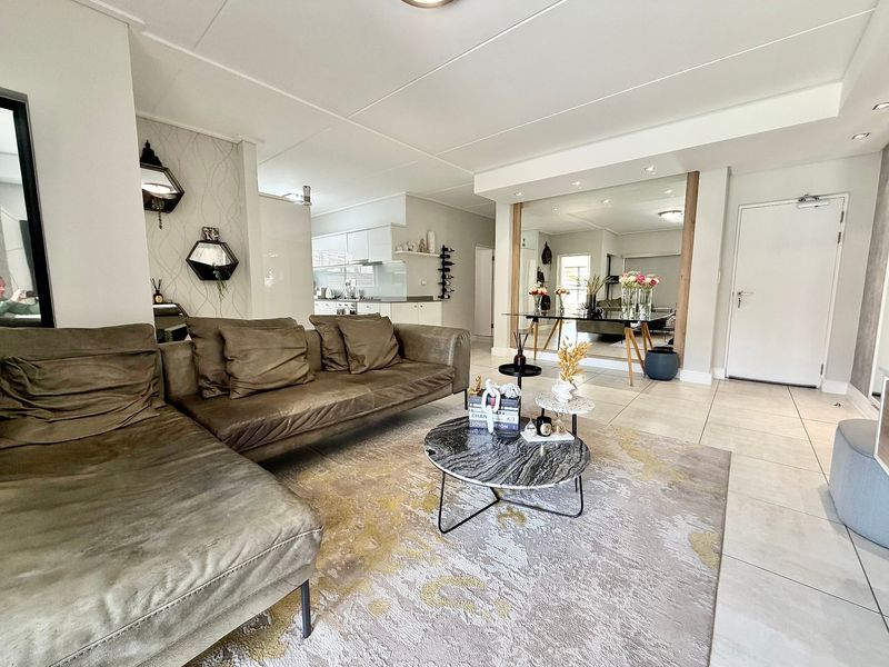 Spacious open-plan living area featuring tiled floors, recessed lighting, and a seamless transition into the modern kitchen space.