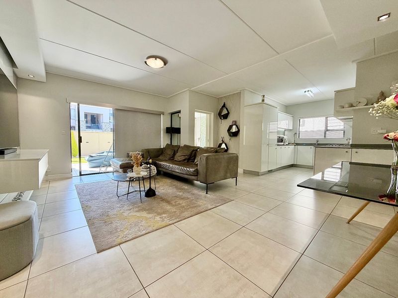 Spacious open-plan living area featuring tiled floors, modern kitchen cabinetry, and a sliding glass door providing access to the outdoor space.